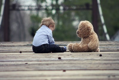 παιδί καθισμένο σε γέφυρα με τραυματικές εμπειρίες που επηρεάζουν τις ενήλικες σχέσεις του
