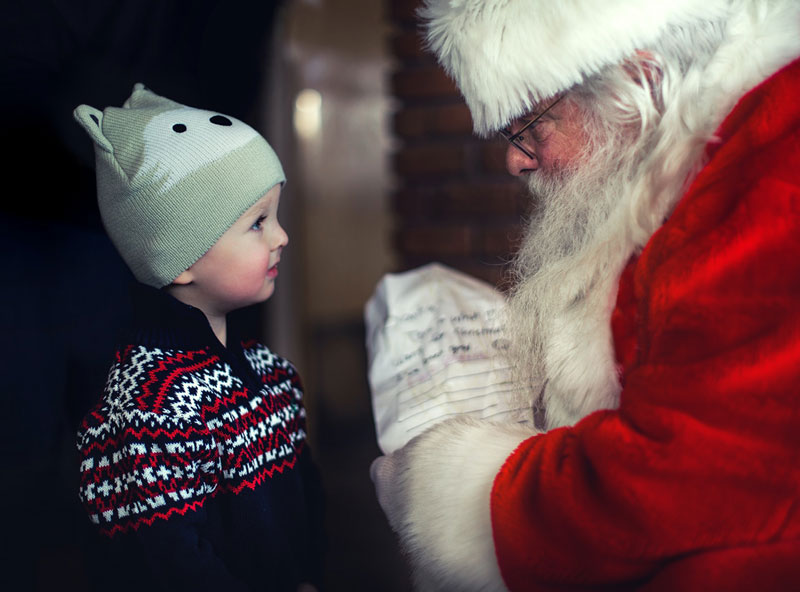 ο Άγιος Βασίλης που δίνει δώρο σε ένα κοριτσάκι μπροστά από το τζάκι