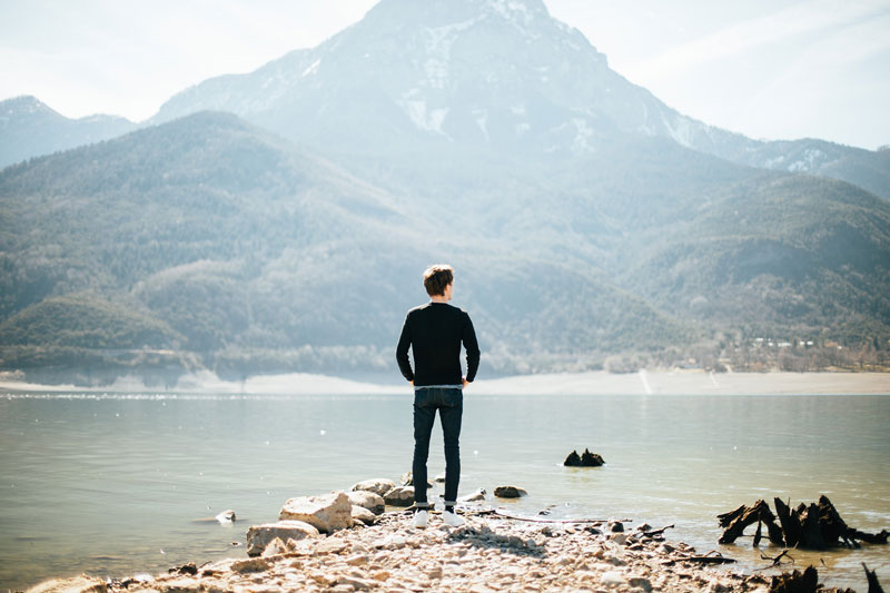 άντρας κάθεται στην άκρη μιας λίμνης