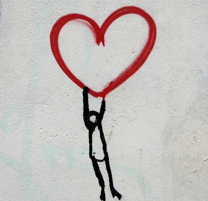 ζωγραφιά που μιλάει για την Αυτό-συμπόνια και ενσυνειδητότητα σε τοίχο με ένα άτομο να κρέμεται από μια καρδιά