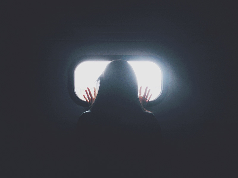 γυναίκα με διαταραχή άγχους κοιτάζει από ένα παράθυρο