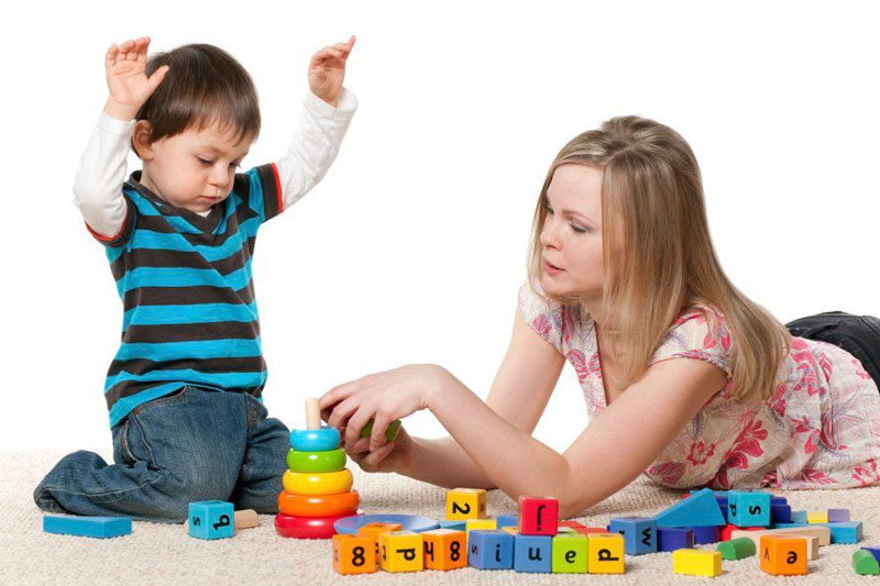 γυναίκα παίζει με ένα παιδί που πάσχει από Διαταραχές Αυτιστικού Φάσματος με παιχνίδια από διάφορα σχήματα