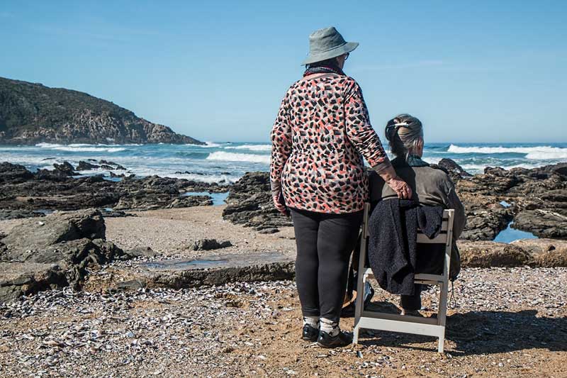 ηλικιωμένη γυναίκα με άνοια στην παραλία βλέπει τη θάλασσα