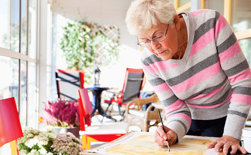 ηλικωμένη γυναίκα ζωγραφίζει στο σπίτι της