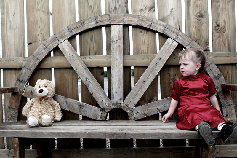 θυμωμένο κορίτσι με κόκκινο φόρεμα κάθεται σε ένα παγκάκι έχει διαταραχές συμπεριφοράς