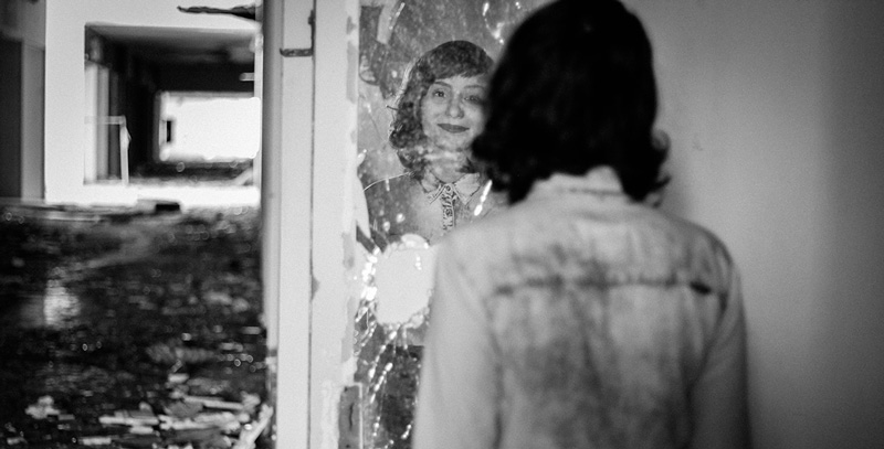 κοπέλα με διπολική διαταραχή κοιτάζει το πρόσωπό της σε ένα σπασμένο καθρεφτάκι και αναρωτιέται εάν πάσχει και από ναρκισσισμό
