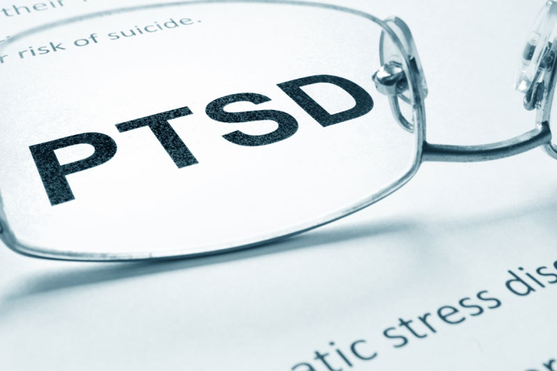 φωτογραφία έντυπου υλικού όπου αναγράφεται η λέξη PTSD και που μεγενθύνεται μέσα από γυαλιά 