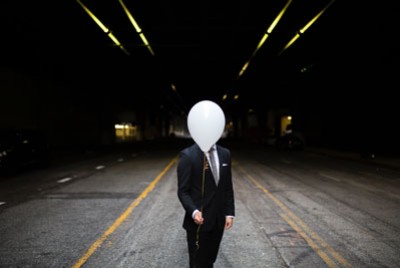 άνδρας με κουστούμι κρατάει ένα άσπρο μπαλόνι που κρύβει το πρόσωπό του πάσχει από κοινωνιοπάθει ή ψυχοπάθεια