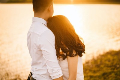 άνδρας και γυναίκα αγκαλιάζονται μπροστά στη θάλασσα την ώρα του ηλιοβασιλέματος δείχνοντας συναισθηματική ασφάλεια στη σχέση