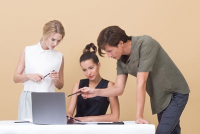 ένας άνδρας που δείχνει κάτι στον υπολογιστή σε δύο γυναίκες