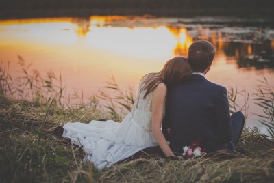 ένα ευτυχισμένο νιόπαντρο ζευγάρι κάθεται στην κοίτη ενός ποταμού