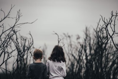δύο παιδιά περπατούν ανάμεσα σε ένα μονοπάτι με δέντρα