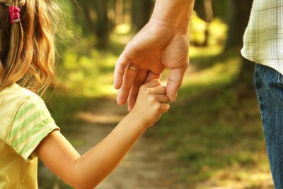 γονέας που δίνει το χέρι του σε ένα κοριτσάκι μέσα σε δάσος