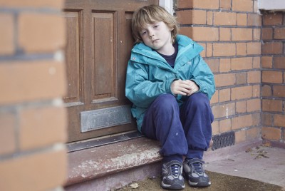 παιδί που κάθεται μόνο και στεναχωρημένο με ψυχική ασθένεια στο σκαλί μίας πόρτας
