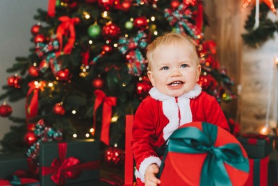 παιδί με δώρο στα χέρια μπροστά από χριστουγεννιάτικο δέντρο