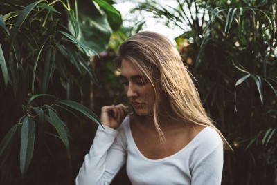 κοπέλα ανάμεσα σε φυτά με λευκή μπλούζα