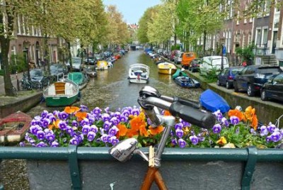 ποδήλατο πάνω σε μια γλάστρα με λουλούδια με φόντο ένα ποταμό