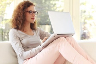 γυναίκα με γυαλιά κάθεται στον καναπέ και κάνει online therap