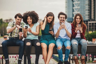 5 νέοι καθισμένοι κοιτούν τα κινητά τους