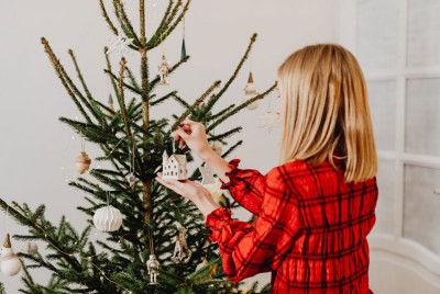 γυναίκα στολίζει το Χριστουγεννιάτικο δέντρο και αναρωτιέται αν τα Χριστούγεννα είναι η πιο καταθλιπτική γιορτή του έτους