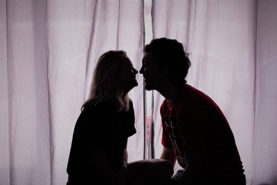 αγόρι και κορίτσι ετοιμάζονται να φιληθούν μπροστά από ένα παράθυρο κλειστό με κουρτίνα