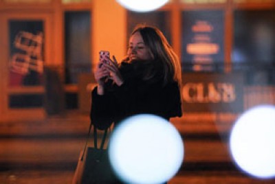 γυναίκα κοιτάζει το κινητό της και τα social media ενώ βρίσκεται στο δρόμο