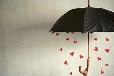 γυναίκα κρατάει ομπρέλα ενώ βρέχει καρδιές