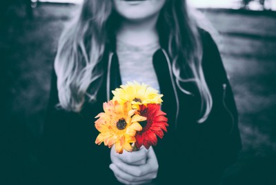γυναίκα με διαταραχή προσωπικότητας σε ασπρόμαυρο φόντο κρατάει ένα κόκκινο και ένα κίτρινο λουλούδι