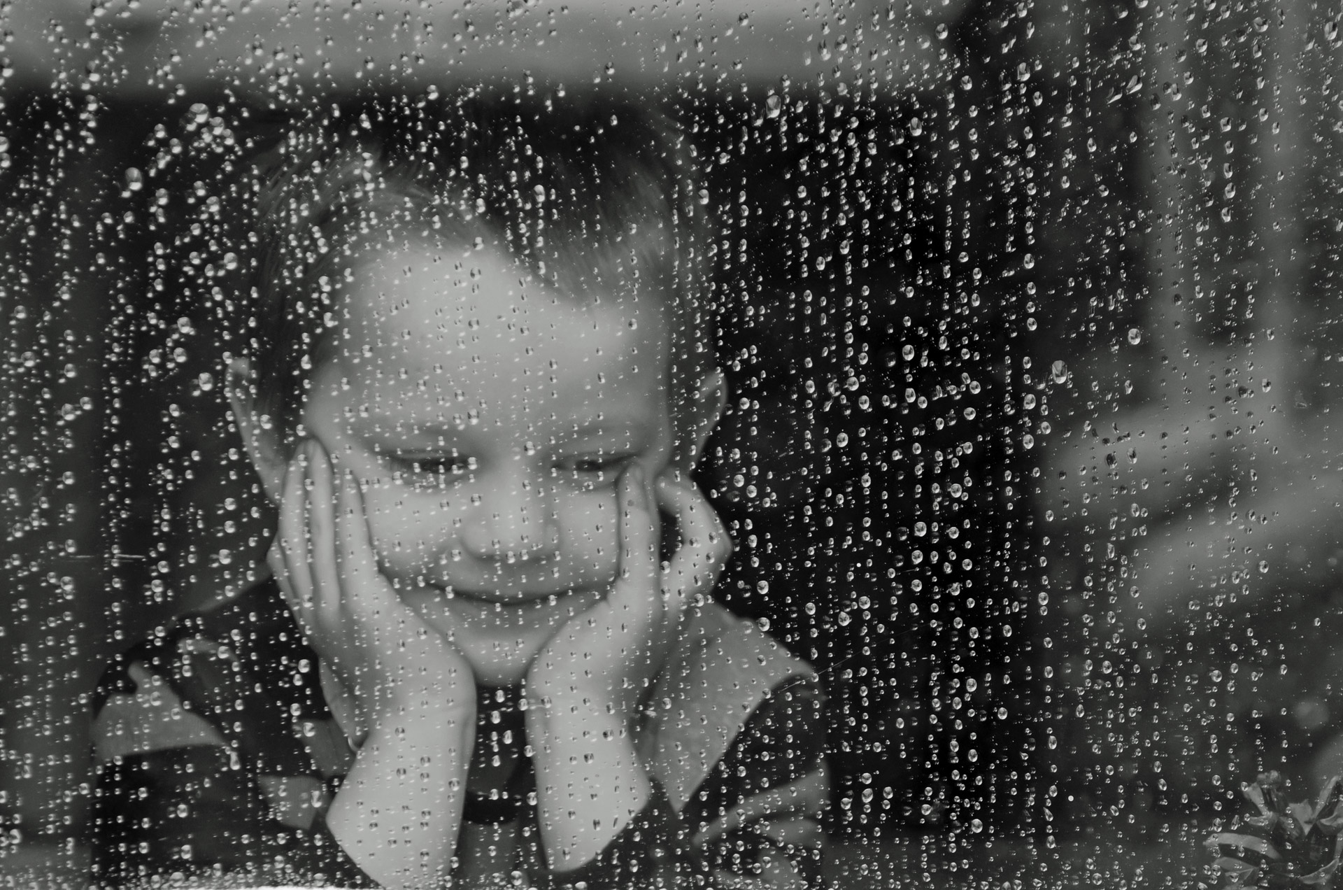 παιδί κοιτάζει από το μπαλκόνι την βροχή και αντιμετωπίζει την απώλεια και το πένθος